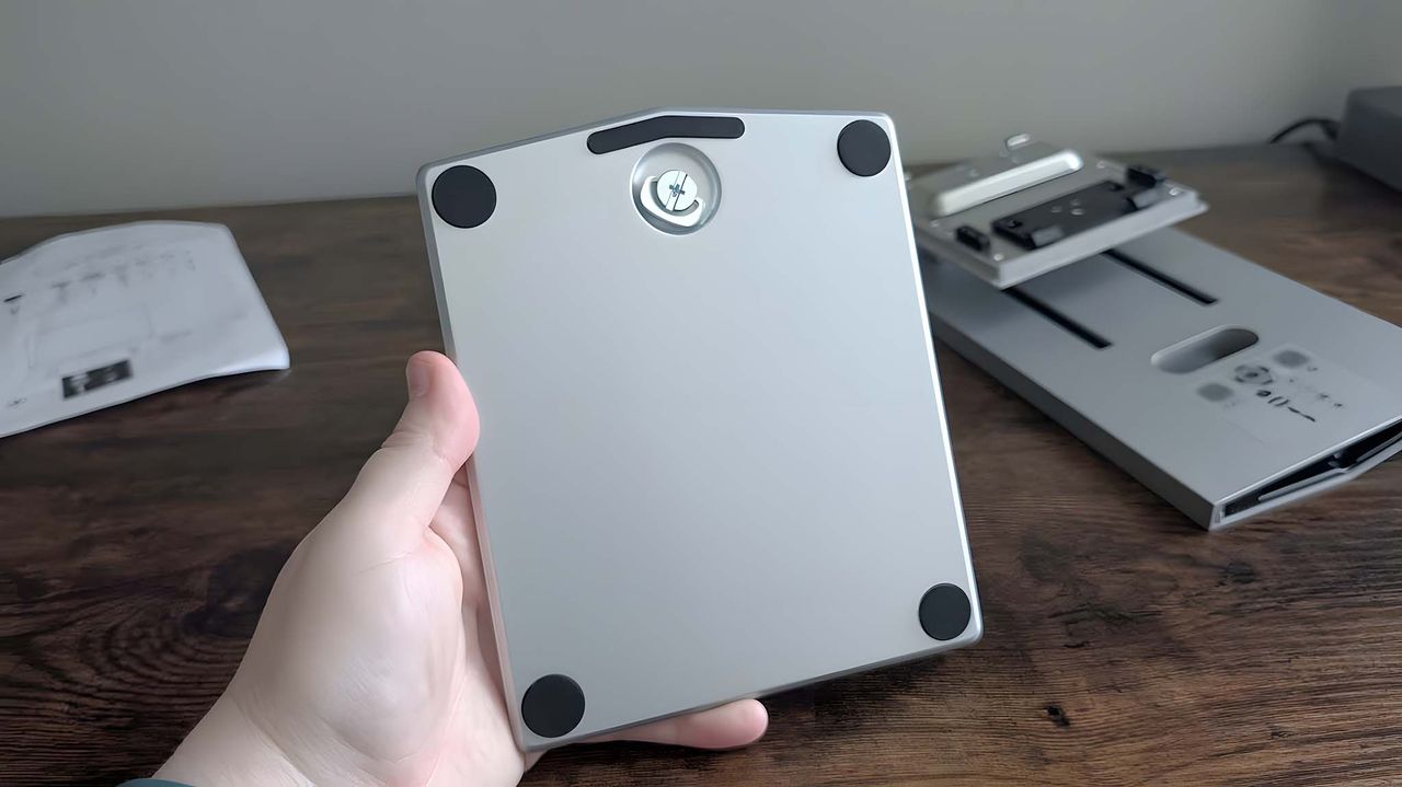 A hand holding the ASUS ZenScreen Smart TV MS27UC base, which has a built-in screw.