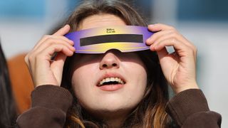A college student observes the solar eclipse with the "pinhole projector" designed by the students made from waste materials in Edirne, Turkiye on October 25, 2022.