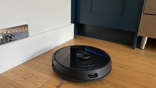 Eufy RoboVac X8 on a wooden floor cleaning a corner of the room