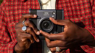 Instax Wide Evo instant camera held in a persons hands