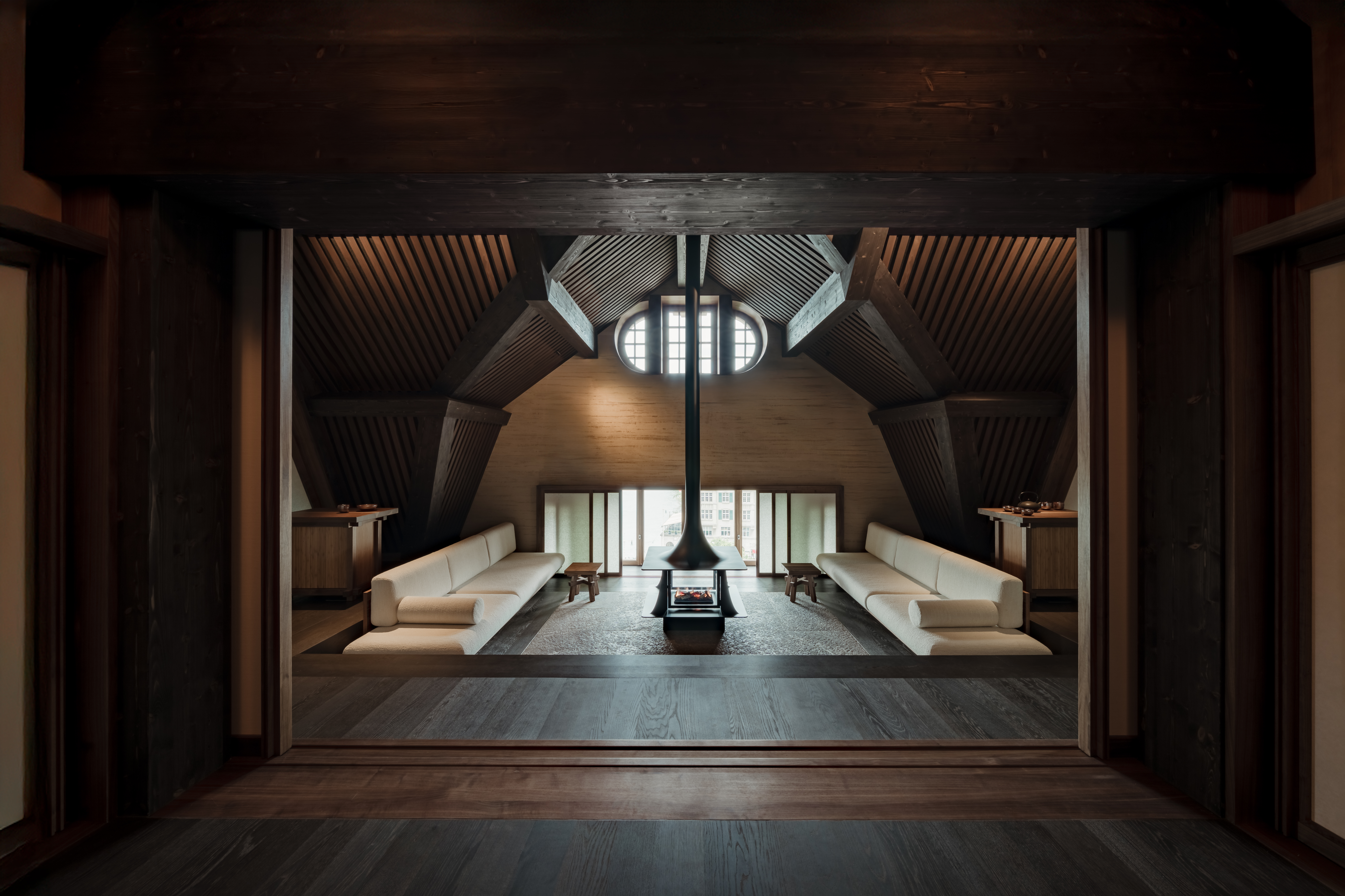 The Seijaku inside Les Trois Rois, a wooden space with a wood burner at the center and long white floor couches.