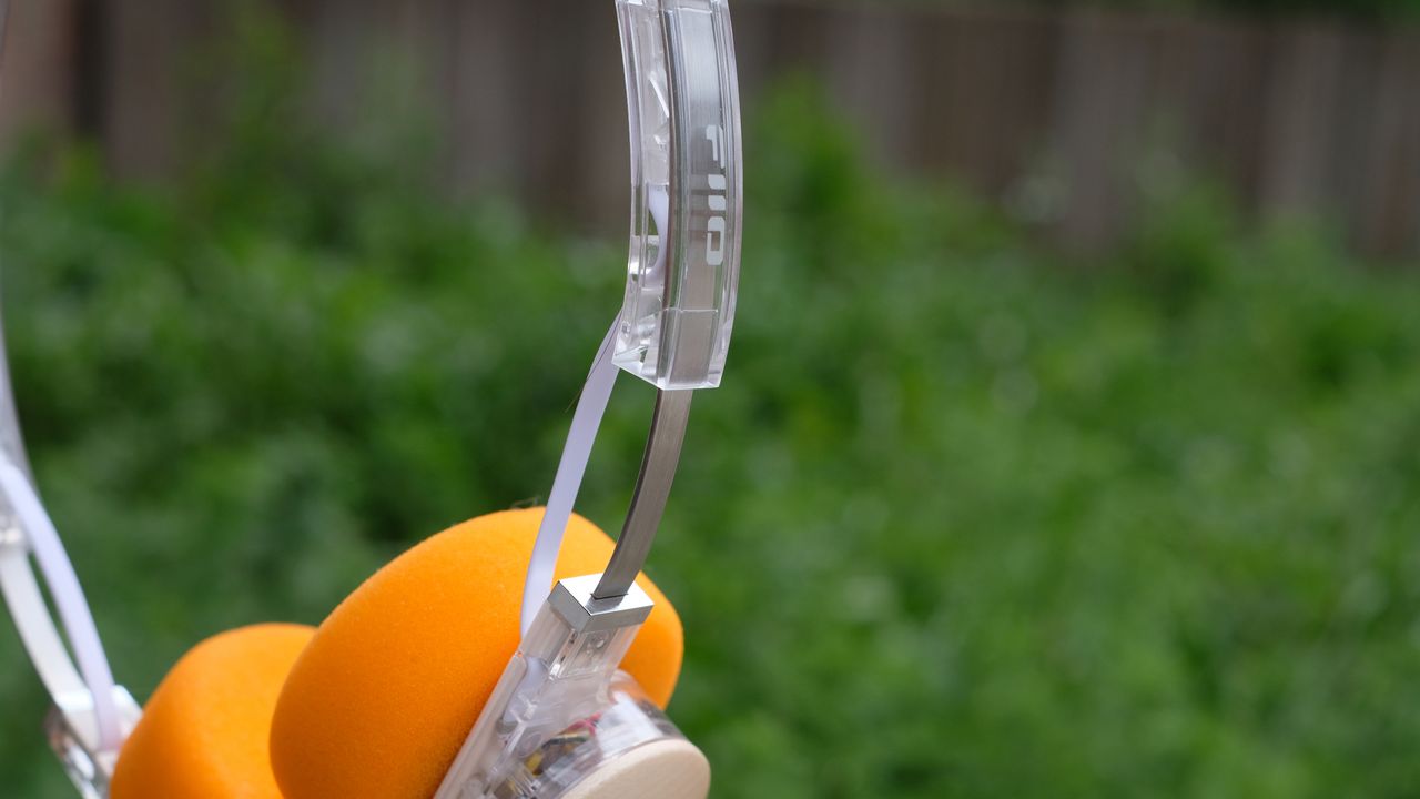 A photograph of the FiiO EH11 over-ear headphones with a transparent frame and orange foam earpads.