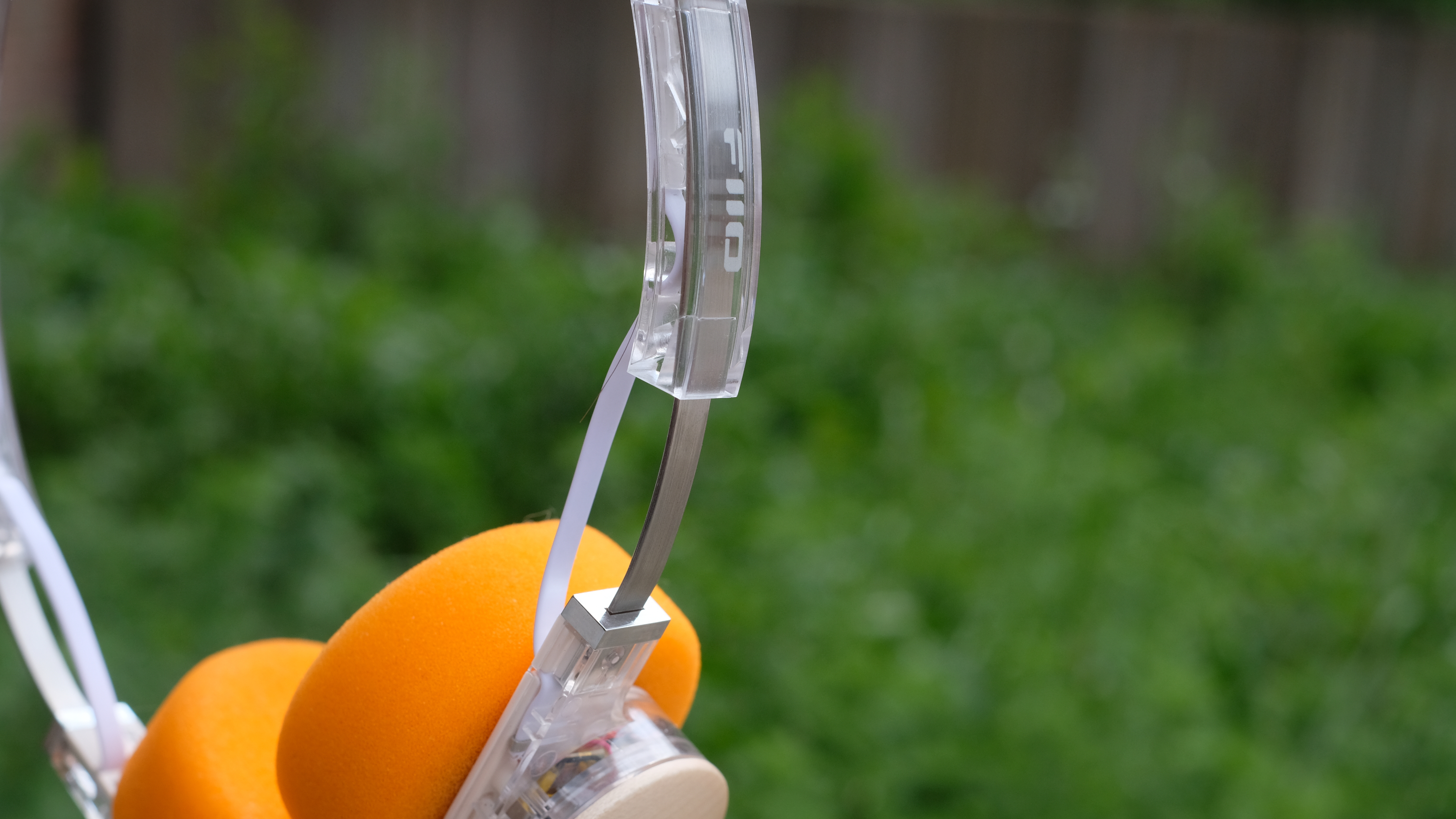 A photograph of the FiiO EH11 over-ear headphones with a transparent frame and orange foam earpads.