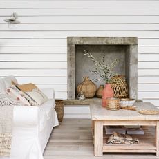 White sofa and wooden coffee table with vases in front of white panelled wall