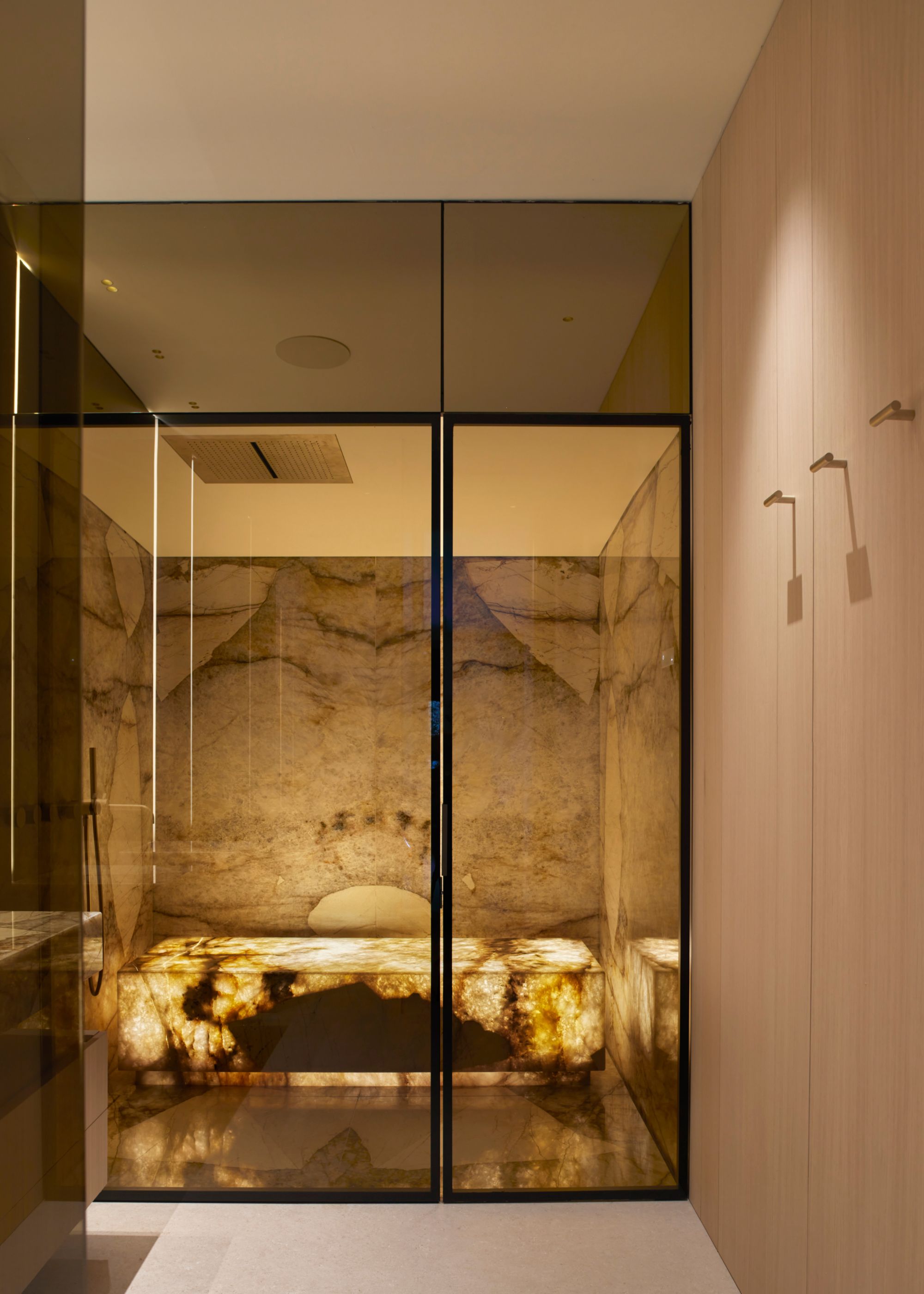 A spa bathroom with a shower bench and backlit marble