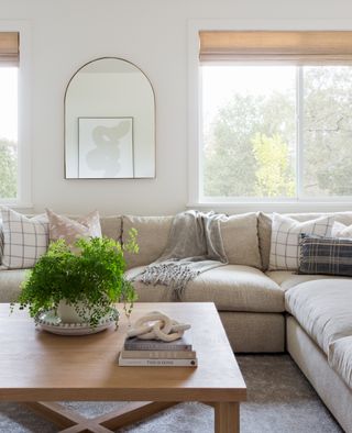 living room with white sectional sofa and pastel cushions with pale wooden coffee table