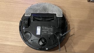 Proscenic Q8 Max robot vacuum flipped over to show mop pad, brushroll and side brush