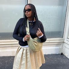 imani wears layered shirt and pleated skirt