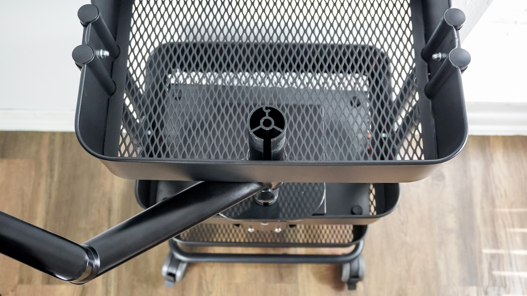 An overhead view of a DIY rollable workstation showing off how the monitor arm comes through a hole drilled in the top shelf