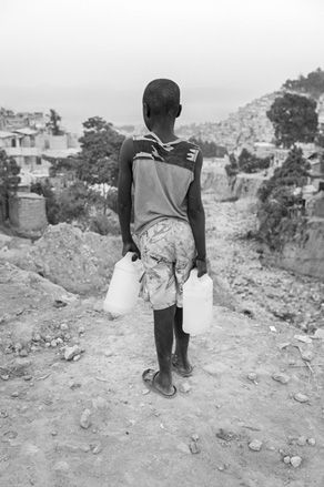 Young boy carrying cartons of water