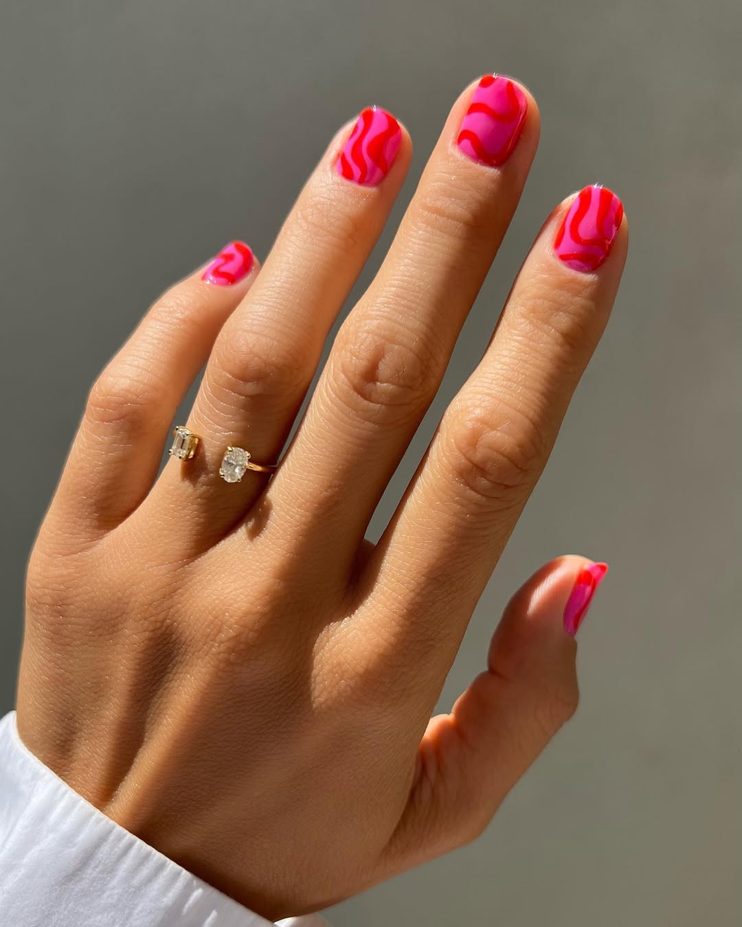 A pink manicure featuring graphic waves by Betina Goldstein
