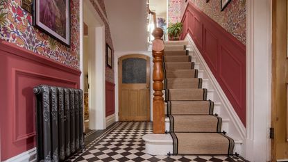 hallway with wooden flooring and navy painted staircase paired with striped grey stair runner