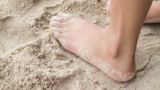 A foot covered with sand on a beach