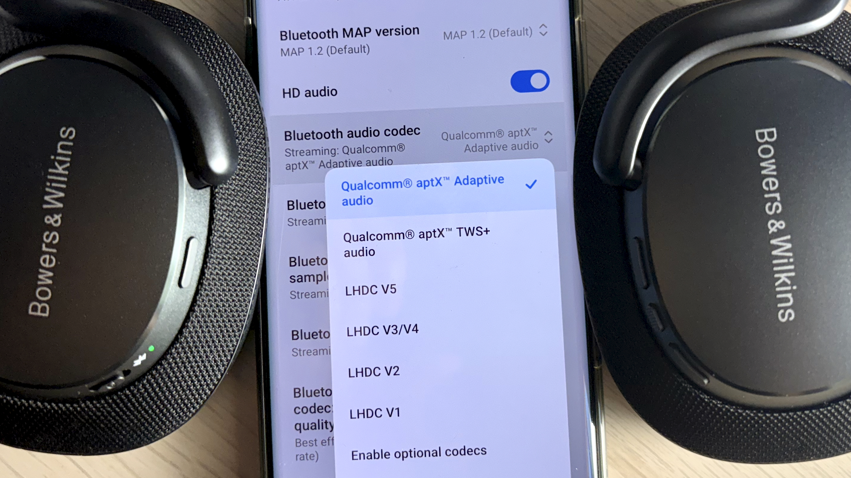 Qualcomm aptX branding, shown on portable hi-fi equipment packaging and a phone screen beside Bowers &amp; Wilkins headphones