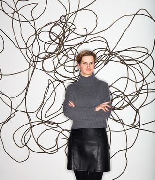 Portrait of Elliott Puckette with her wall mounted, three-dimensional cast bronze sculpture Random Walk, 2021