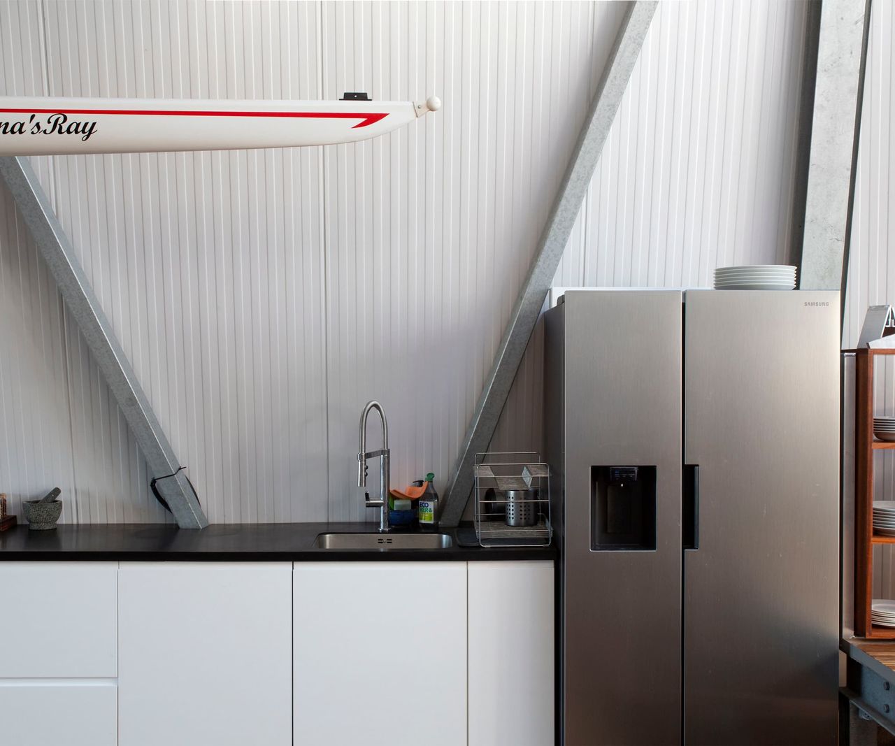 A kitchen with aluminium walls and a matt fridge