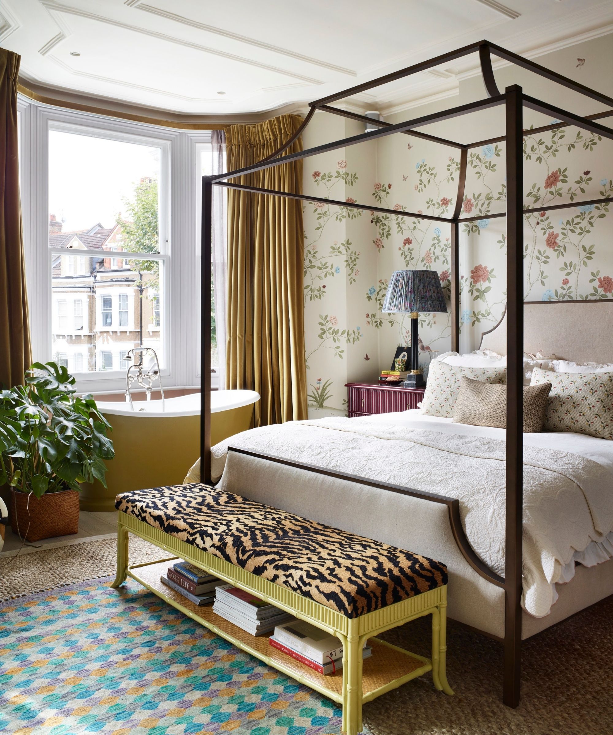 floral mural wrapped bedroom with a four poster bed frame, layered rugs, a yellow bathtub and a yellow bench with a tiger print upholstered top