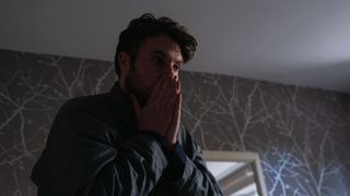 James with his hands to his face in shock as he finds Maria dead on her sofa