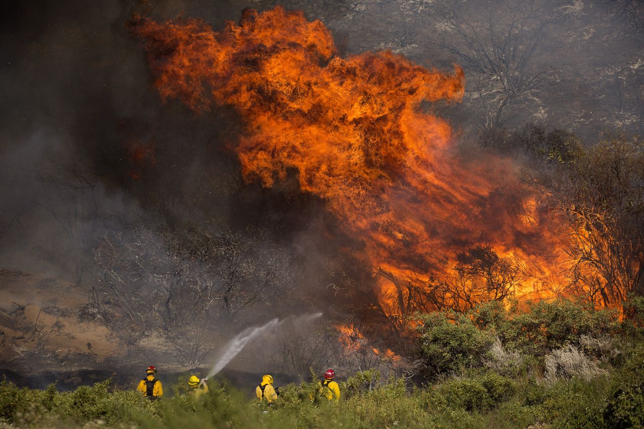 Firefighters battle the Apple fire.