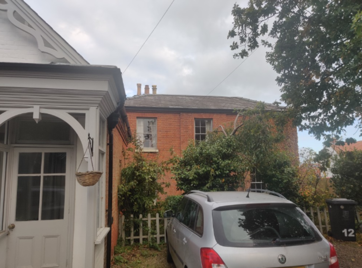 A brick house with flat roof and 3 chimney sets