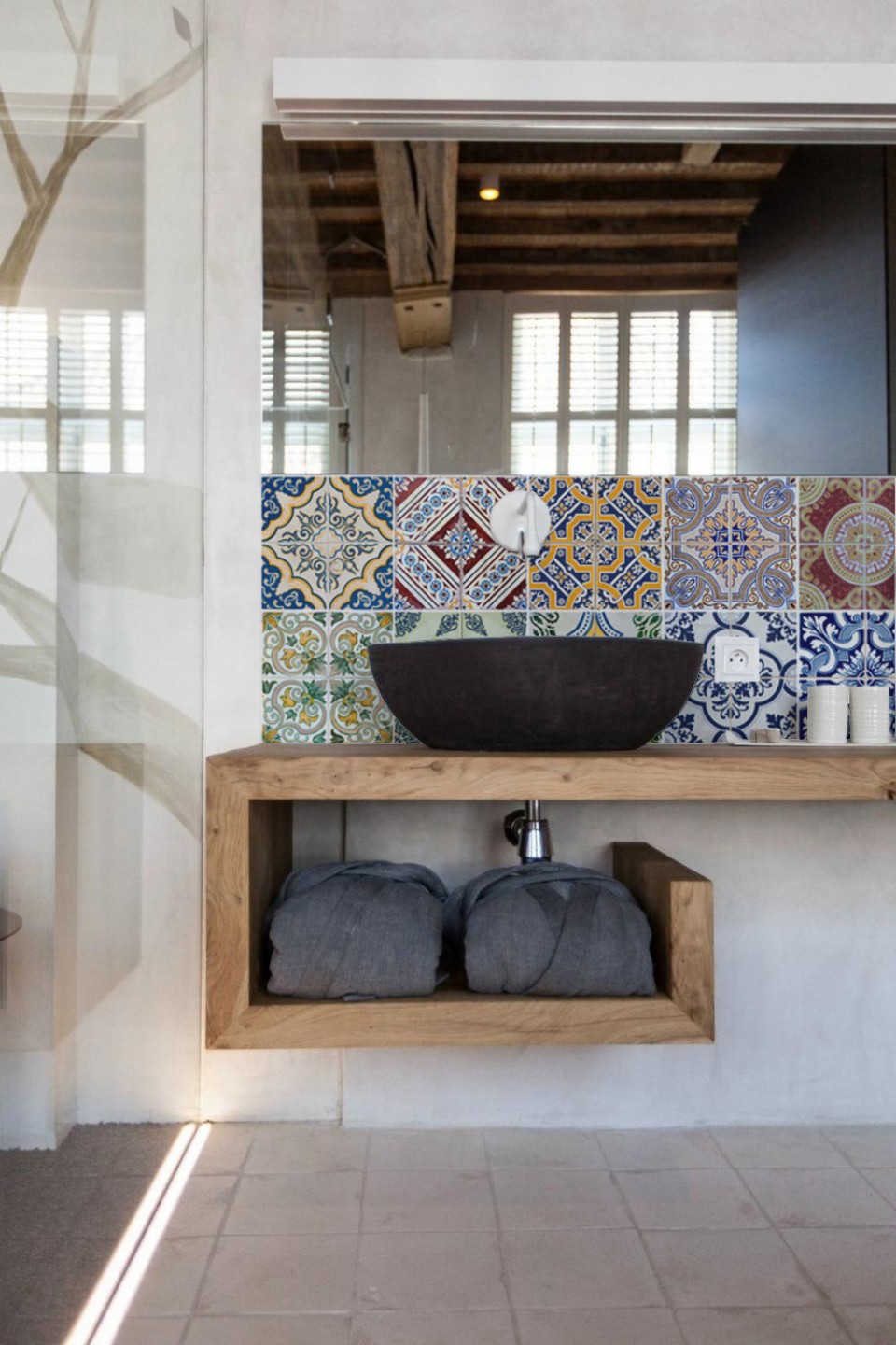 Mosaic tiles in a small bathroom with large windows and freestanding sink