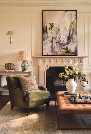 A peach walled living room with green armchair and coordinating lamps and wall lights