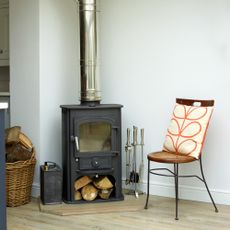 wood burning stove next to chair and log basket