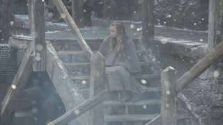 Lonely girl sitting on wooden stairs in the snow