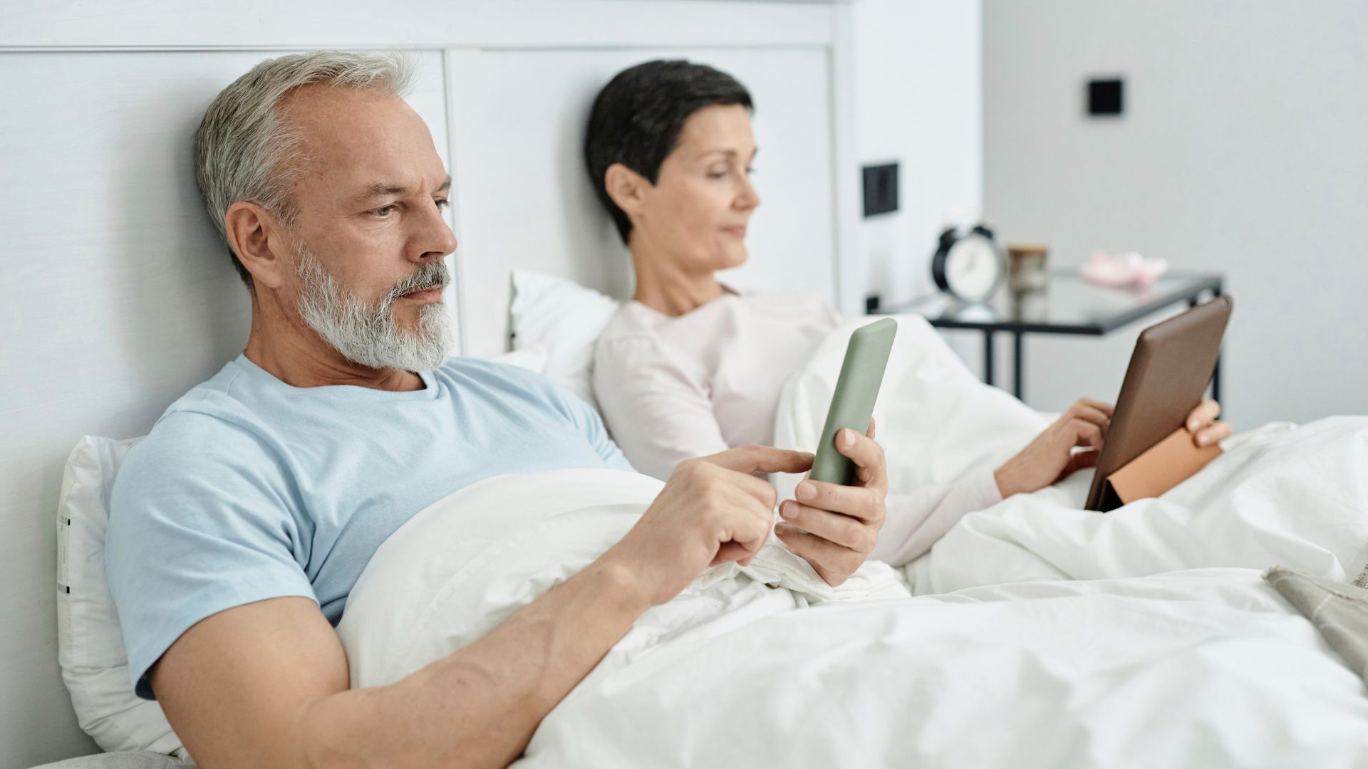 Couple in bed using smartphones