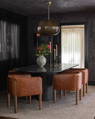 A dining room with black walls and ceiling, and tan chairs