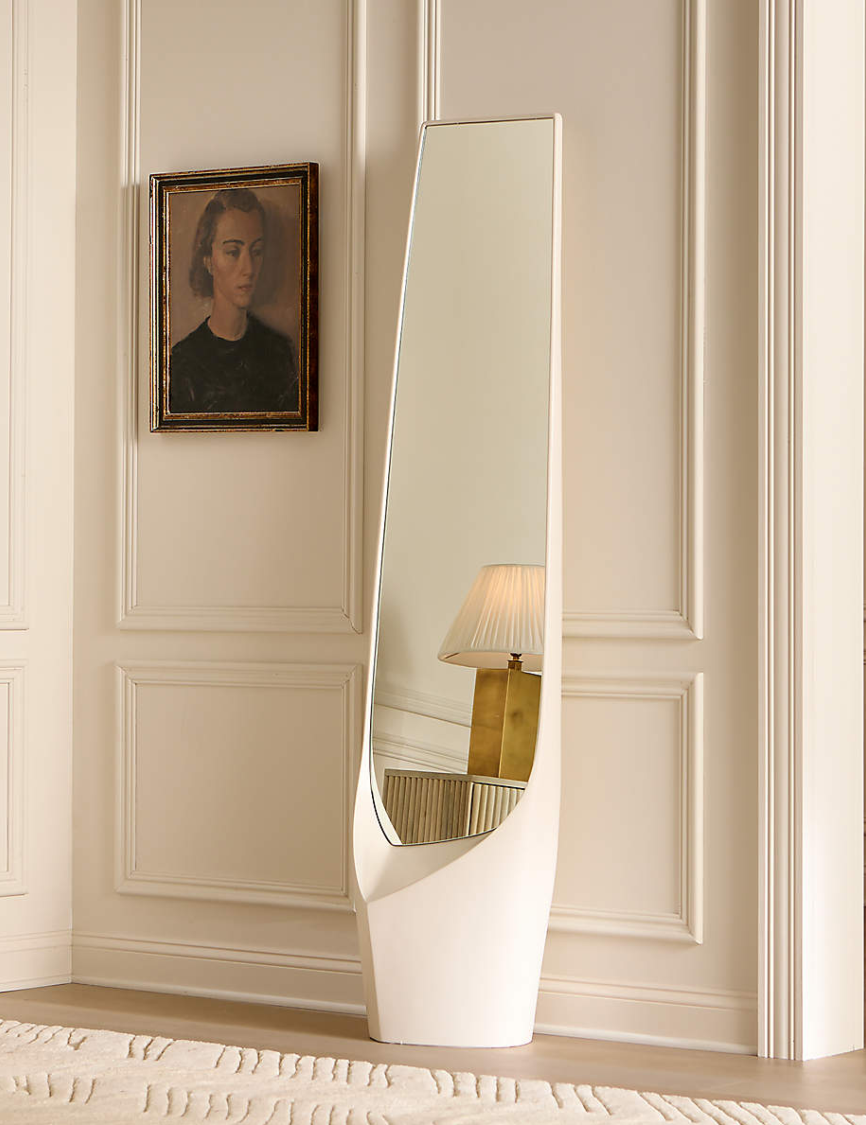 White interior featuring a classic oil painting and  decorative molding, juxtaposed by a sleek modern resin floor mirror