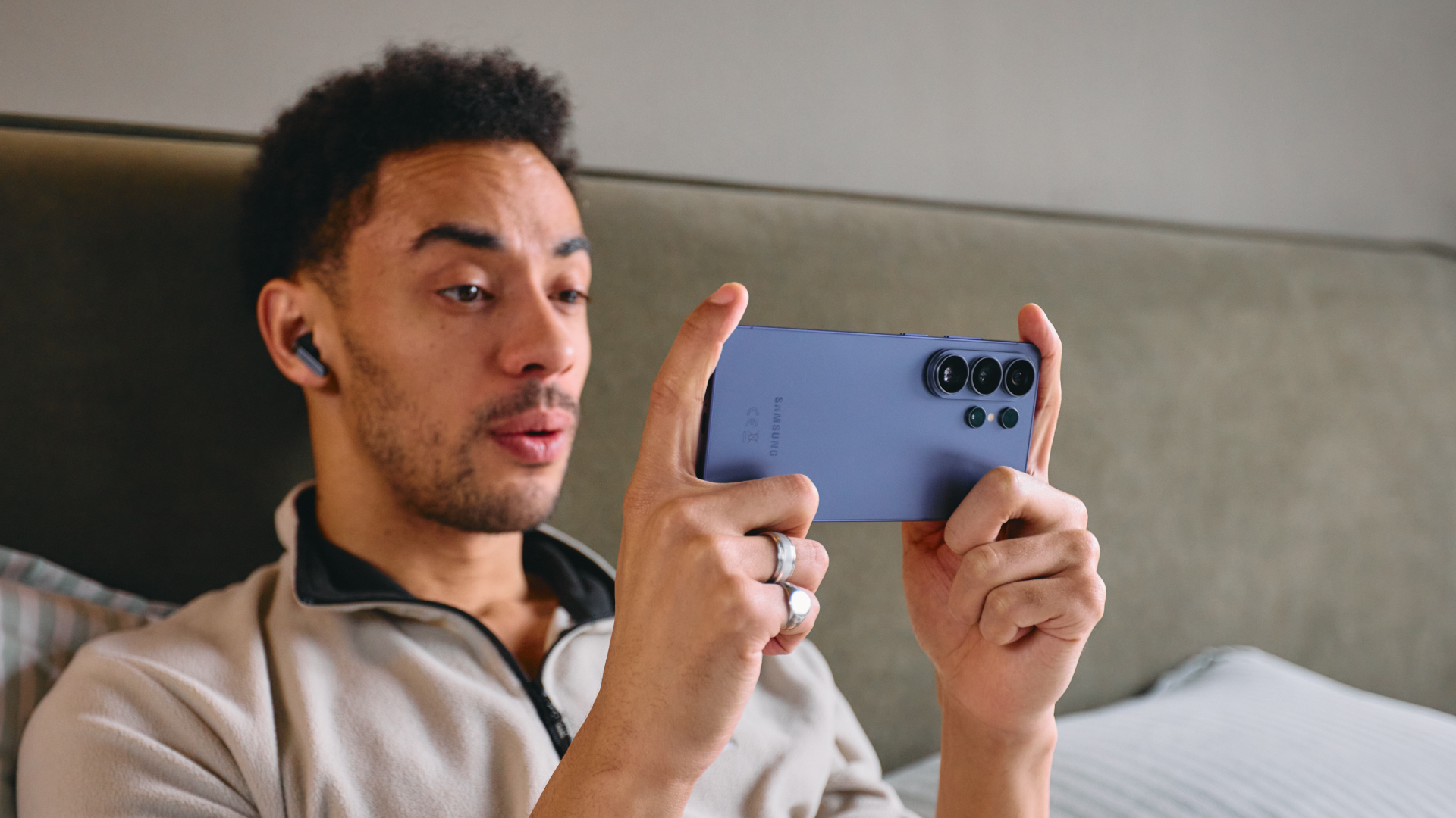 A man sits in bed, playing a game on his Samsung Galaxy S26 Ultra