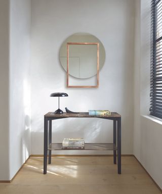 A small entryway with a mirror, blinds, and a small console table