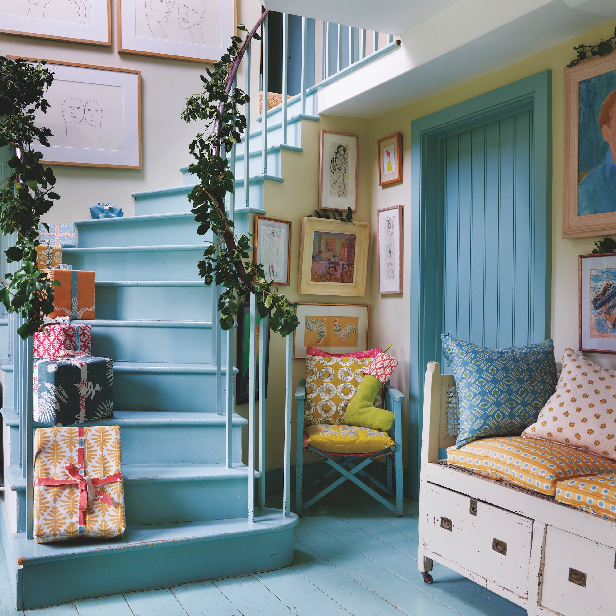 hallway with wooden staircase painted pale blue, with blue floor and woodwork, wooden bench seat and Christmas presents on stairs