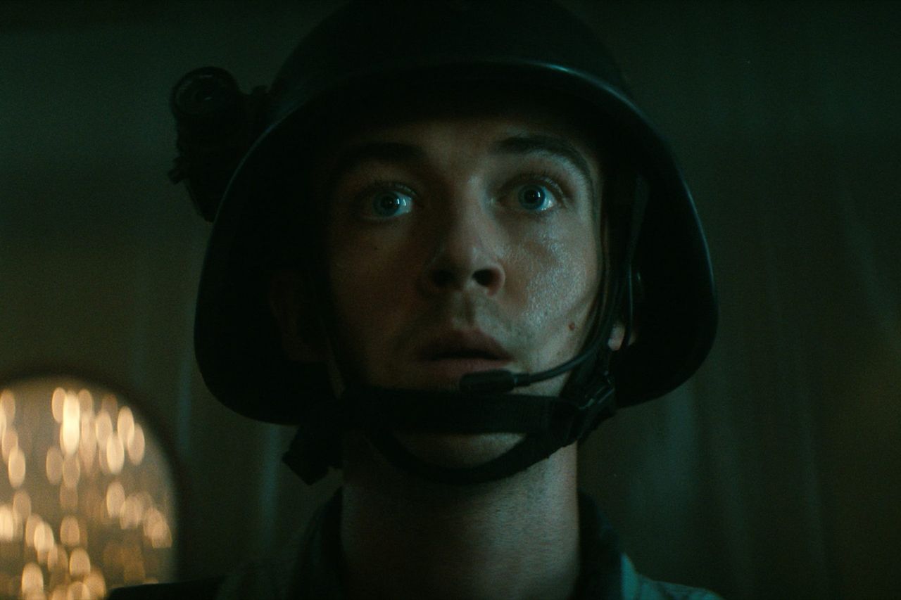 Still from the TV show Alien: Earth. Close up of a dazed soldier. They are wearing a helmet with a small camera attach to the side.