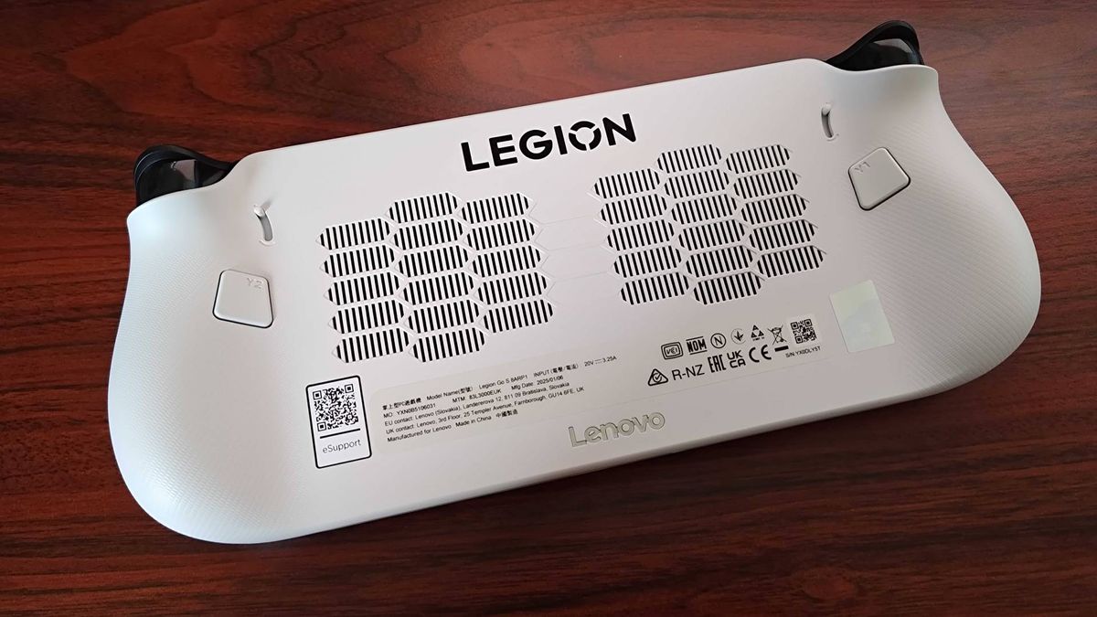 Lenovo Legion Go S flipped onto front with back panel facing upwards on woodgrain desk.