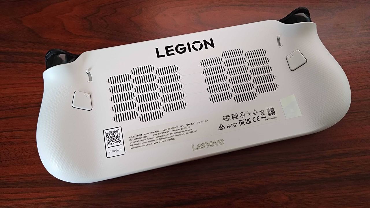 Lenovo Legion Go S flipped onto front with back panel facing upwards on woodgrain desk.
