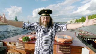 An image of Dave Myers with his arms wide open on a boat from The Hairy Bikers' Northern Exposure Russia.