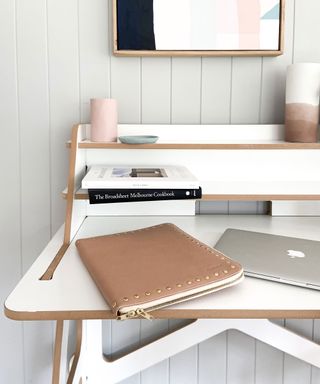 Zoomed in on modern white desk, notepad apple macbook and books on desk