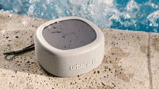 The Urbanista Malibu bluetooth speaker in grey pictured next to a swimming pool.