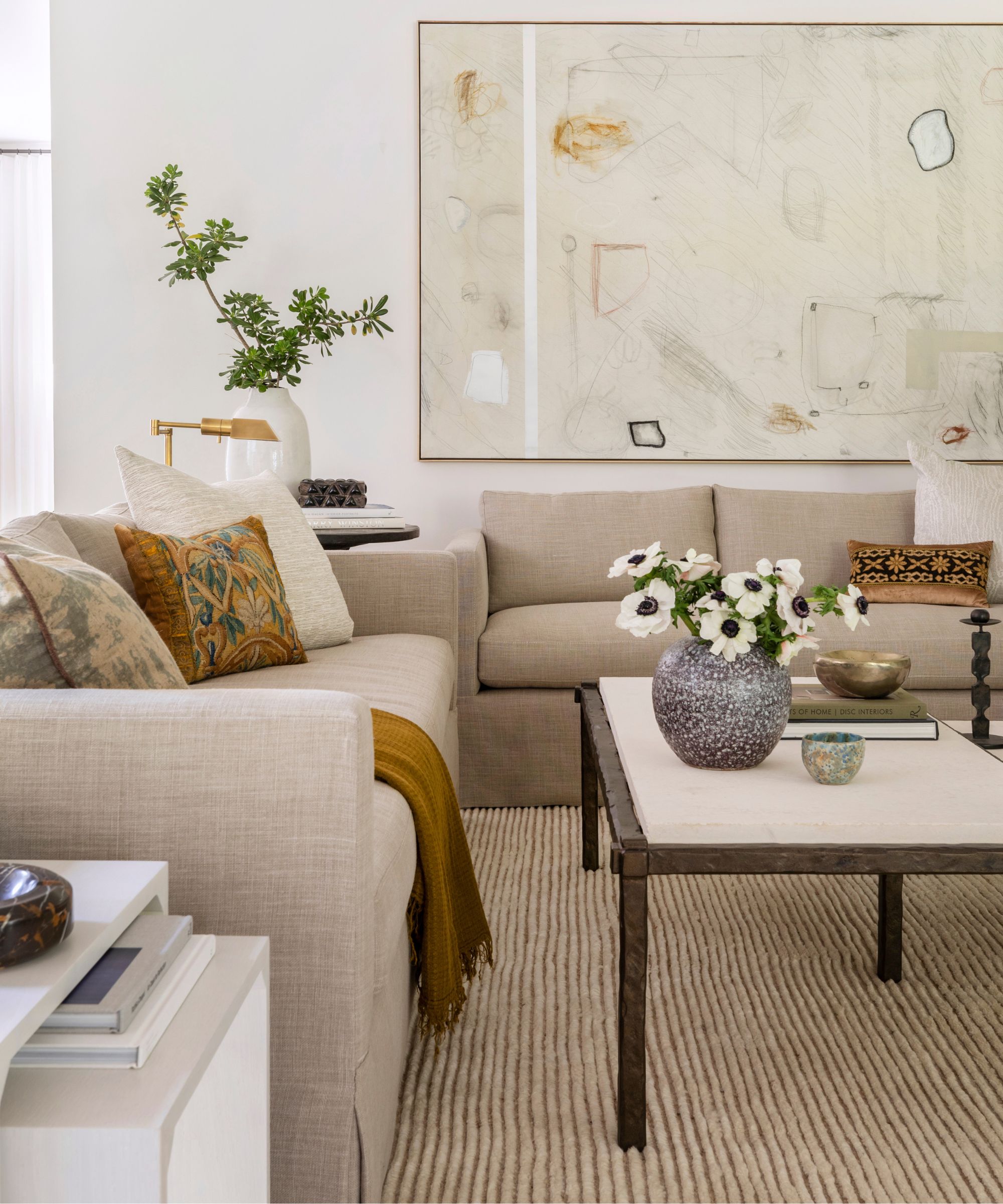 neutral living room designed by Marie Flanigan with two beige linen sofas, a metal coffee table, large abstract neutral art and a neutral texture ribbed rug