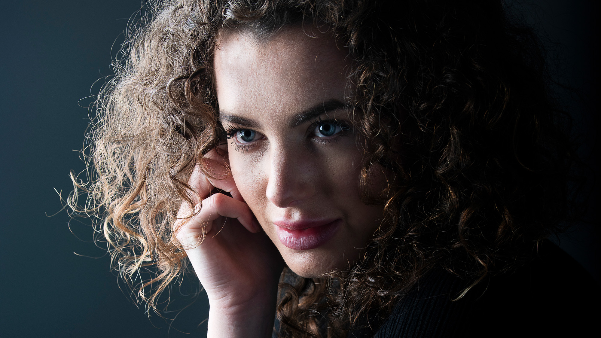 Close-up studio portrait of model by James Paterson on a dark grey background