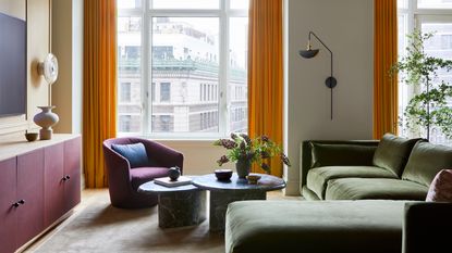 Living room with olive green chaise longue sofa, grey marble coffee tables, purple armchair and orange curtains