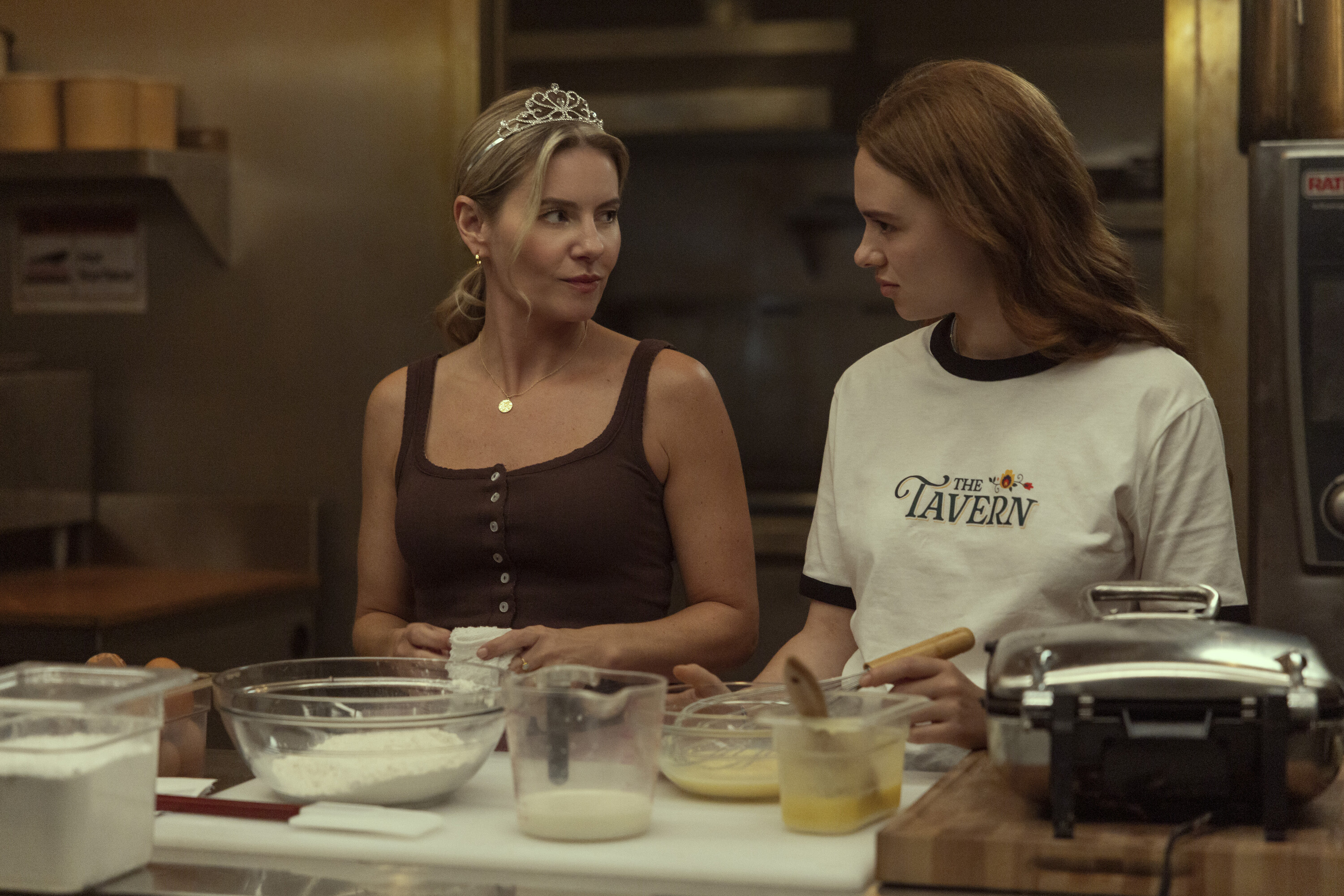 Elisha Cuthbert as Sue wearing a tiara along with Sadie Soverall as Percy cooking in a kitchen in 'Every Year After.'