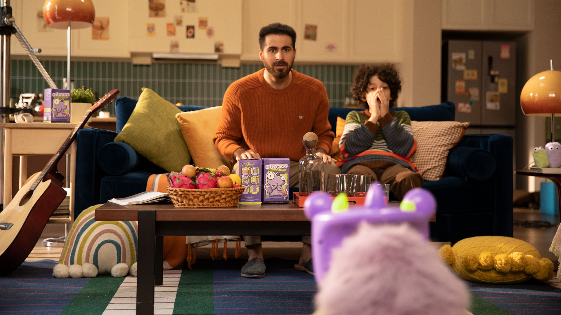 A father and son sitting on a couch, looking at the OlloBot OlloNi SS1 in the foreground