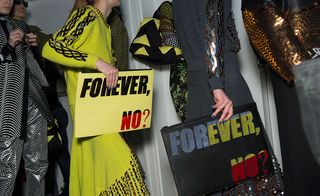 Models wear yellow and black intricate jacquards, embroideries, sequin bedazzled knitwear whilst holding a " Forever No?" sign