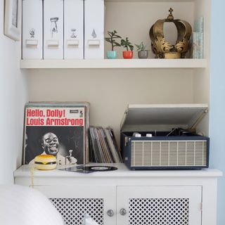 white shelves with record players and vinyls and a white cabinet underneath