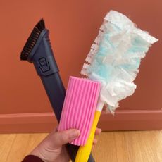Hand holding a flash dust magnet, scrub daddy damp duster and a Shark vacuum dusting tool