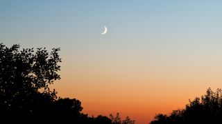 new moon in sunset sky