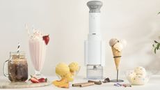 A tall white Cuisinart ice cream maker surrounded by milkshakes, slishes, and ice cream. 